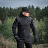 Mies pukeutuneena M-Tac Norman Windblock -fleecetakkiin ulkona metsässä, sopii siirtymäkausiin ja kylmiin olosuhteisiin.
