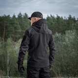 Henkilö pukeutuneena M-Tac Norman Windblock -fleecetakkiin luonnossa, takaa nähtynä.