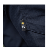 Yksityiskohta M-Tac Bukser Aggressor Dame Flex -housuista, M-Tac-logo tummansinisellä kankaalla.