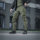M-Tac Rubicon Flex innovatiivisella cargo-taskulla, sopivat treeniin ja työhön oliivinvärisenä, esitetty ulkona.