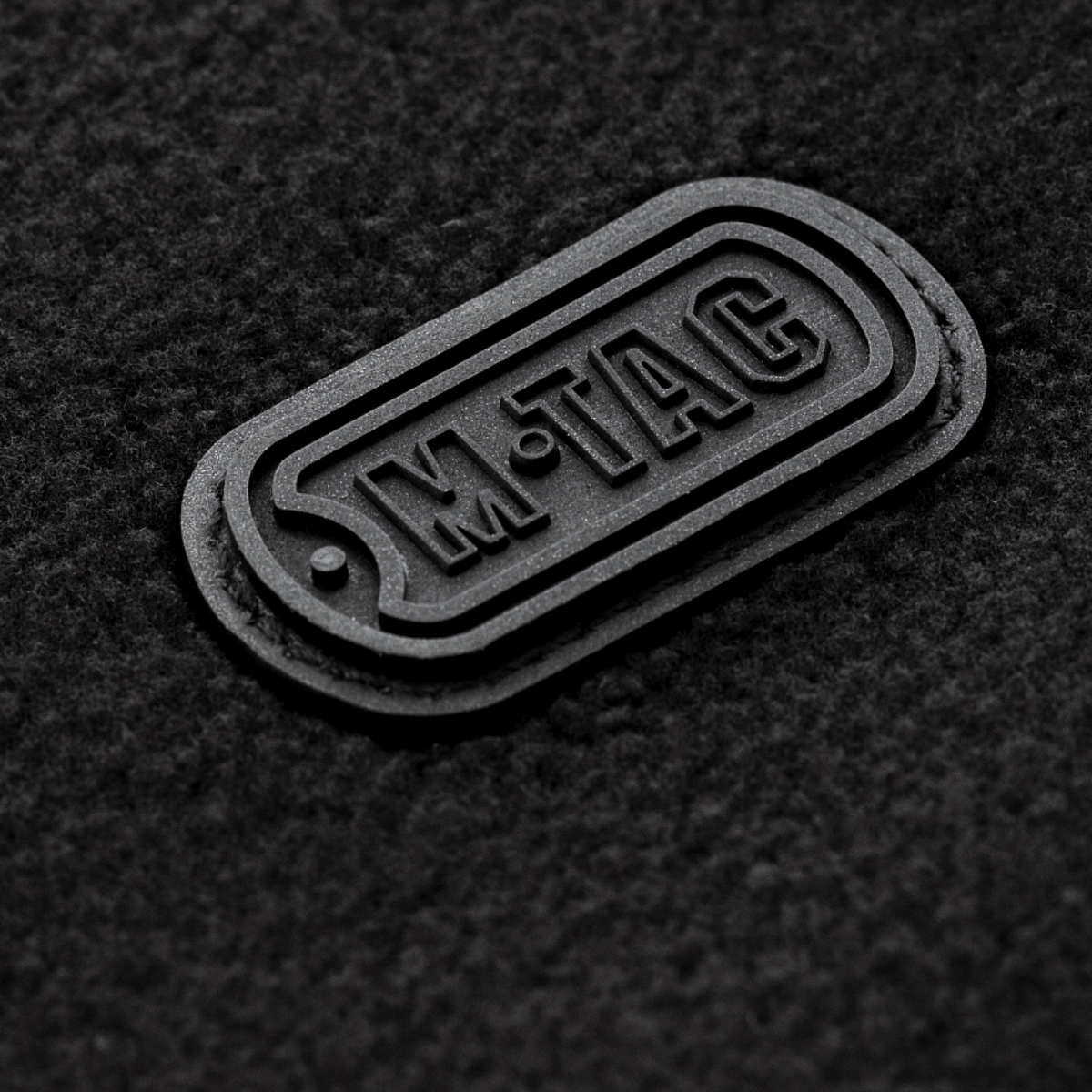 M-Tac Alpha Microfleece Jakke Gen.II logo-yksityiskohta fleece-pinnalla, moderni takki taktiseen ja ulkoilukäyttöön kylmällä säällä.