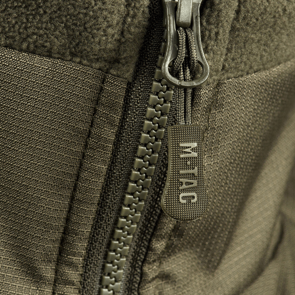 Vetoketjun yksityiskohta M-Tac Alpha Microfleece takki Gen.II:stä, korostaa kestävää rakennetta ja taktista muotoilua.