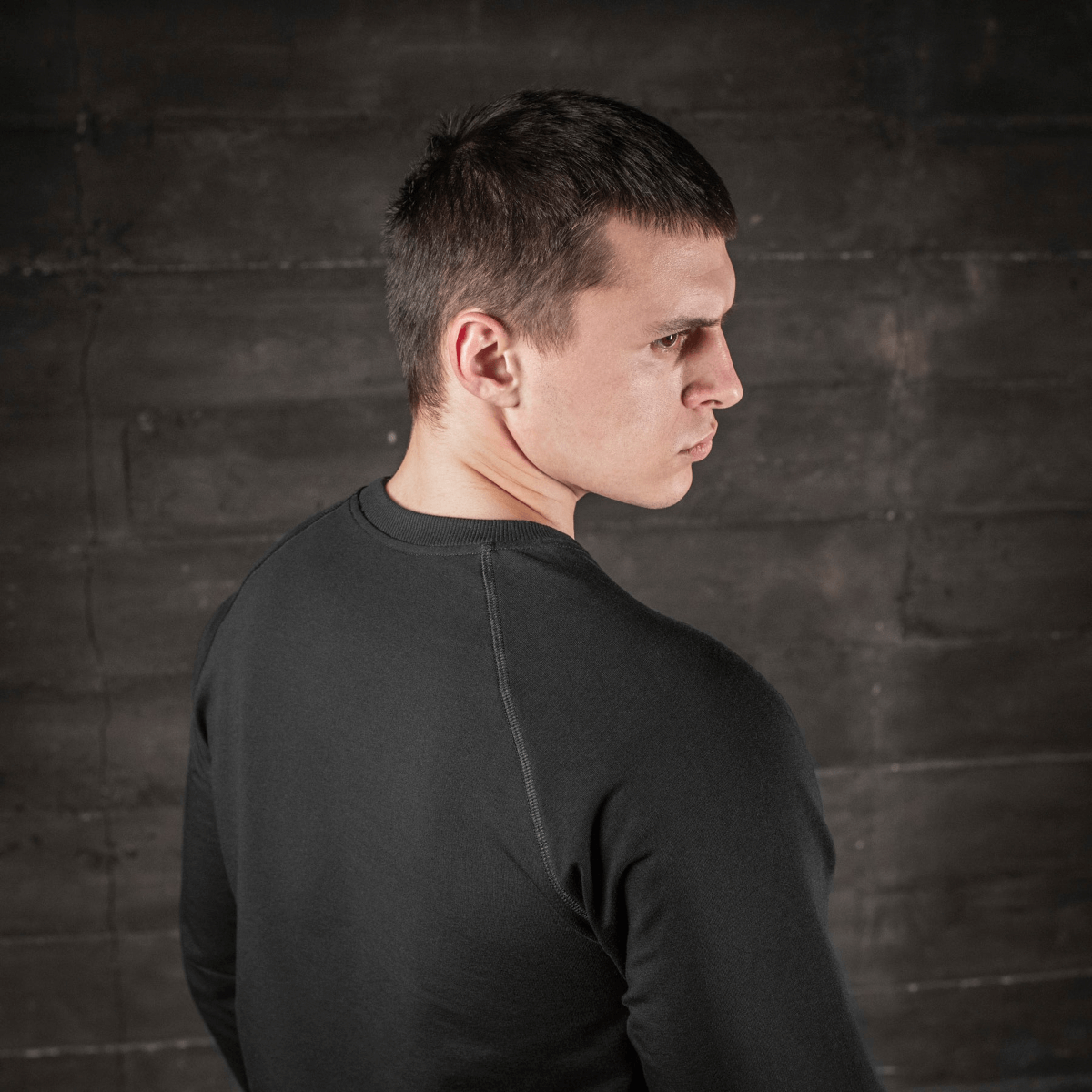 Mies pukeutuneena M-Tac Raglan Athlete -musta college raglanhihoilla, takaa nähtynä, sopii urheiluun ja arkeen.