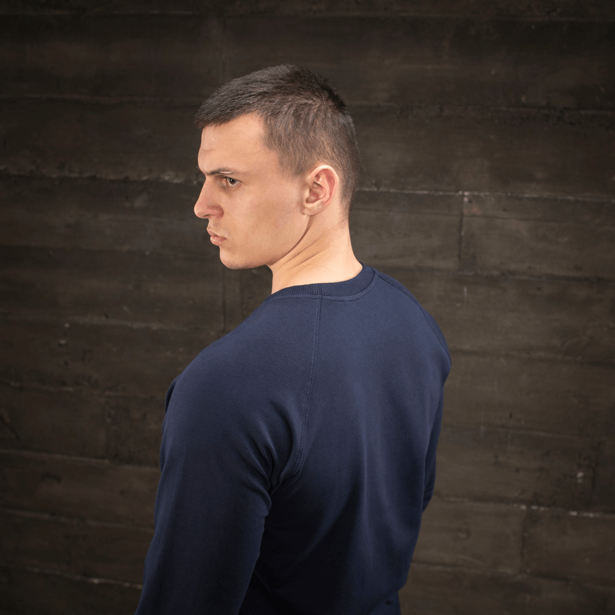 Mies pukeutuneena M-Tac Raglan Athlete -laivastonsininen college pyöreällä pääntiellä ja raglanhihoilla, sivulta nähtynä, sopii urheiluun ja arkeen.