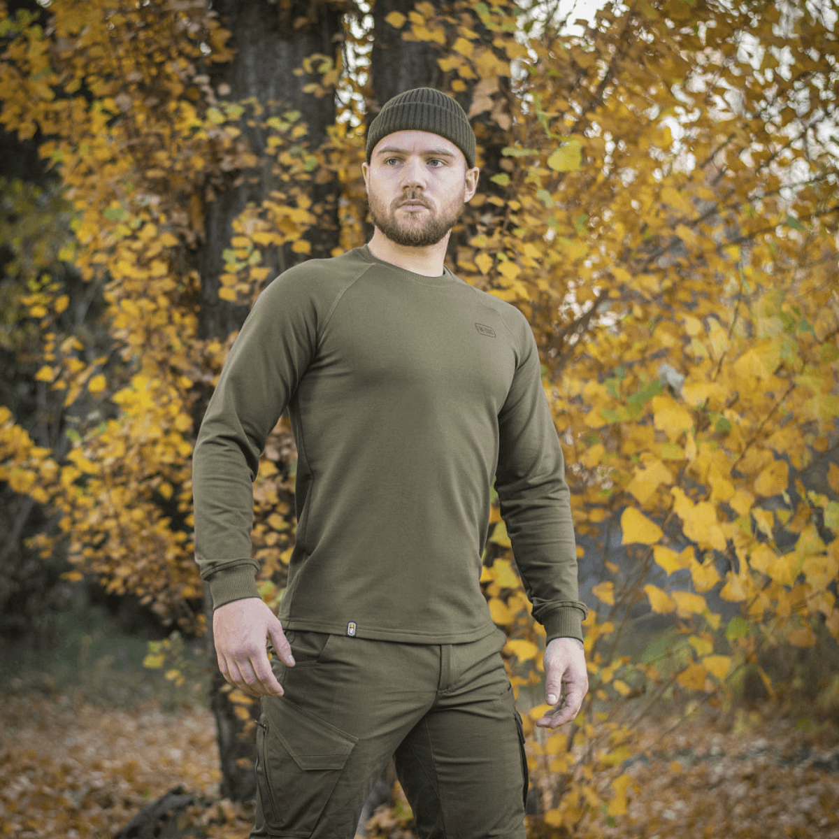 Mies pukeutuneena M-Tac Raglan Athlete -oliivinvihreä college syksyllä.