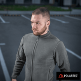 M-Tac Nord Polartec -fleecetakki harmaana, valmistettu Polartec® 200 Series -fleecestä, pidetty miehen yllä parkkipaikalla.