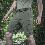 Mies pukeutuneena M-Tac Aggressor Summer Flex Shorts -shortseihin metsässä, kevyet ja hengittävät taktiset shortsit.