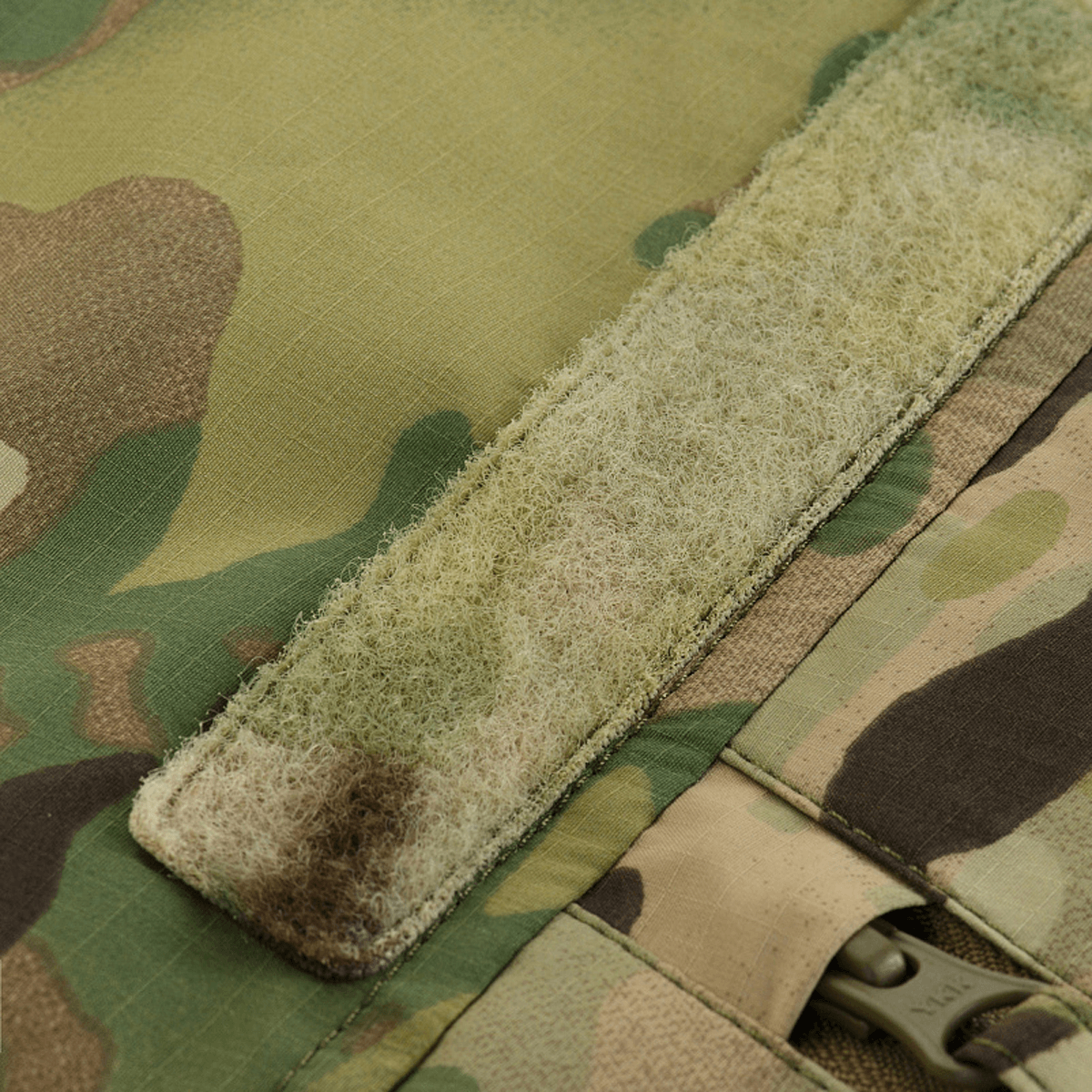 Yksityiskohta M-Tac Alpha Gen.IV Pro Primaloft -talvitakista alkuperäisellä Multicam-kuosilla ja kestävä tarrakiinnitys.