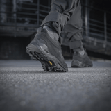 Mies kävelee betonipinnalla M-Tac Tactical Sneakers Patrol R Vent -kengät jalassaan, näkyy kestävä kumipohja.