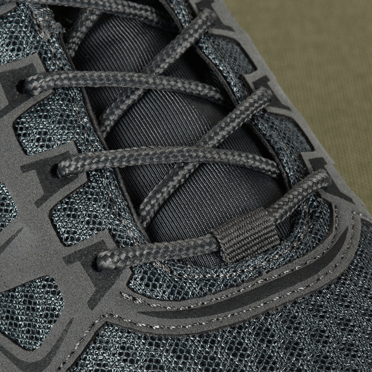 Yksityiskohta nauhoituksesta M-Tac Tactical Sneakers IVA:ssa, hengittävä verkko ja synteettinen nubukki päällisosassa.