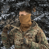 Mies käyttää M-Tac Anatomisk Snood Justerbar Elite Fleece (320 g/m²) metsäympäristössä, esittelee monikäyttöistä muotoilua kylmään säähän.