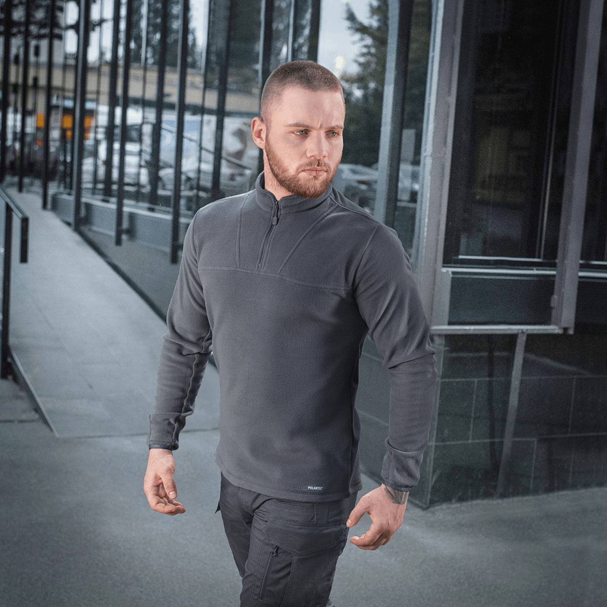 Mies pukeutuneena M-Tac Delta Polartec -fleece-takkiin harmaana, moderni tausta.