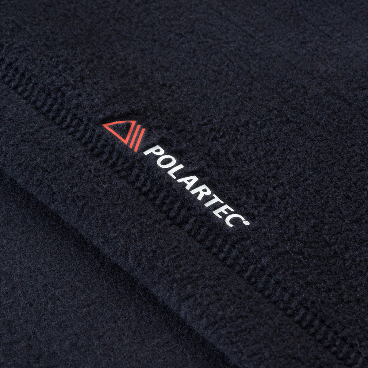 Lähikuva M-Tac Delta Polartec -fleece-takin Polartec®-logosta; valmistettu Polartec® Micro Series -fleecestä.