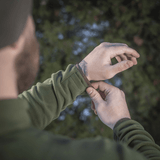 Mies säätää hihansuutta M-Tac Delta Polartec fleece-takissa metsässä, näyttää takin toiminnallisen suunnittelun ja materiaalin.