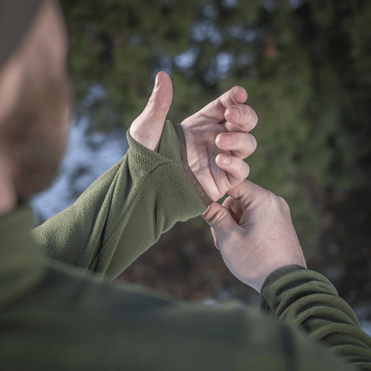 Mies pukeutuneena M-Tac Delta Polartec fleece-takkiin säätää hihansuut luonnossa.