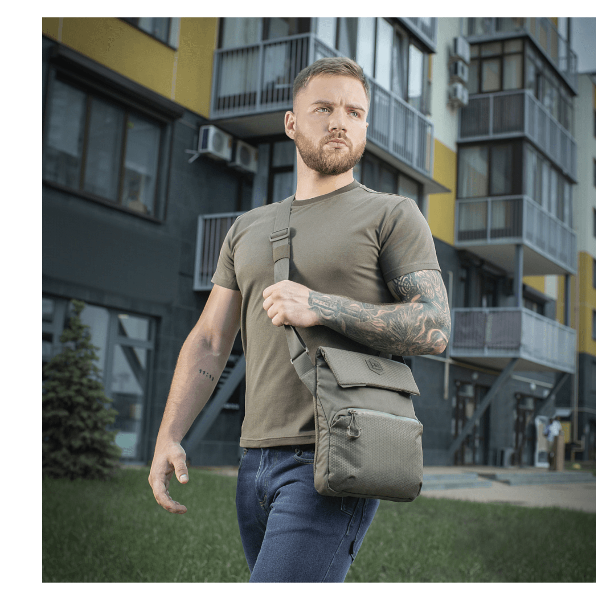 Mies kantaa M-Tac Konvert Taske Eliteä harmaassa kaupunkiympäristössä, moderni tablettilaukku valmistettu Cordura-materiaalista.