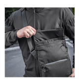 Mies kantaa M-Tac Konvert Taske Eliteä Cordura 500D:llä, näyttää magnetventilin nopeaa käyttöä varten, säädettävä olkahihna.