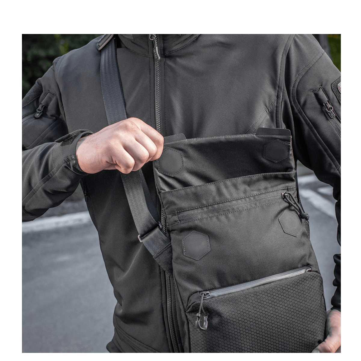 Mies kantaa M-Tac Konvert Taske Eliteä Cordura 500D:llä, näyttää magnetventilin nopeaa käyttöä varten, säädettävä olkahihna.