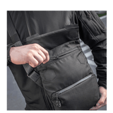 Mies kantaa M-Tac Konvert Taske Eliteä, valmistettu kestävästä Cordura-materiaalista, magnetlukning ja säädettävä olkahihna.
