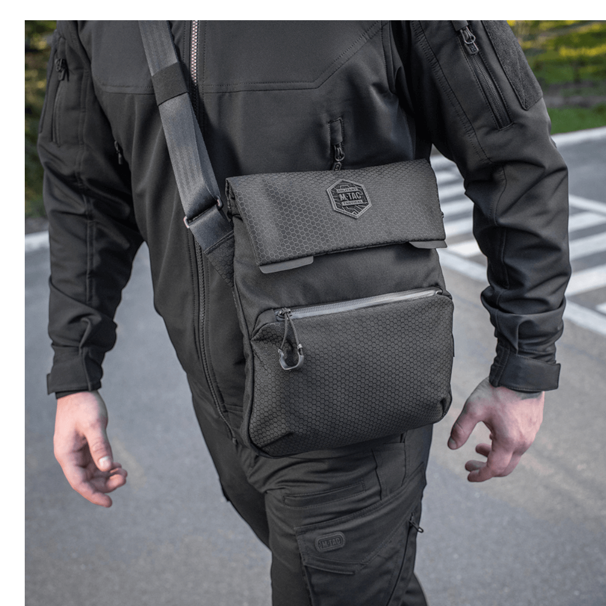Mies kantaa M-Tac Konvert Taske Eliteä mustana, säädettävä olkahihna, Cordura 500D ja Cordura Hex 1000D.