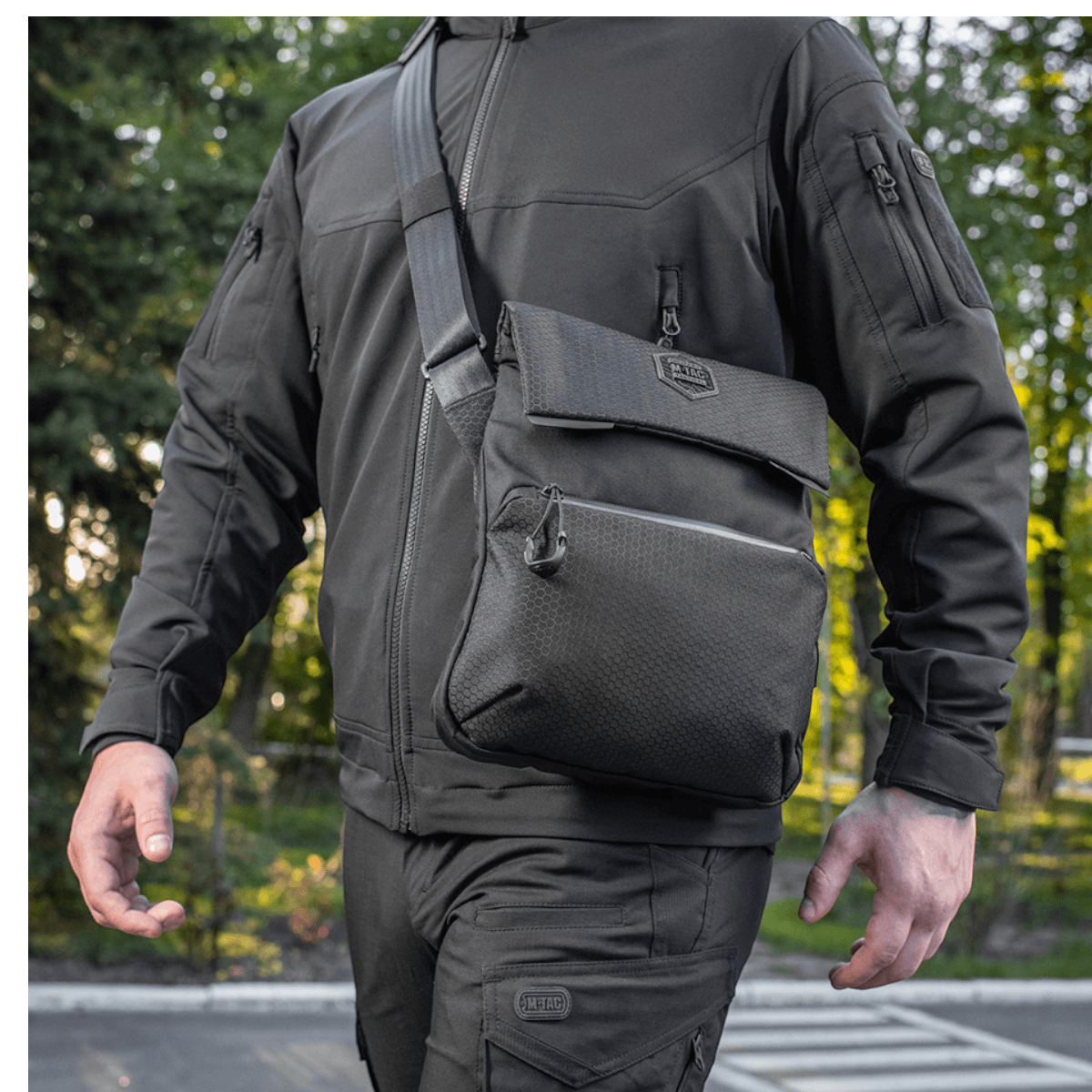 Mies kantaa M-Tac Konvert Taske Eliteä Cordura-materiaalista, säädettävä olkahihna ja tablet-design, ulkokuvassa.