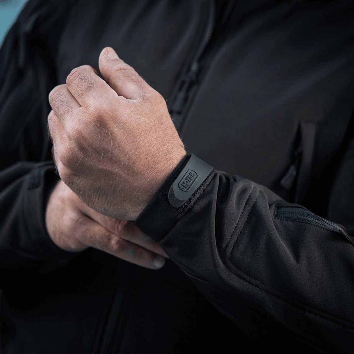 Mies säätää M-Tac Soft Shell -takin hihansuita, näyttää kevyen mallin ja sääsuojaa antavan materiaalin.