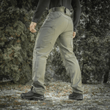M-Tac Soft Shell Vinter -housut metsäympäristössä, korostaa housujen lämpöä ja mukavuutta kylmissä, tuulisissa olosuhteissa.