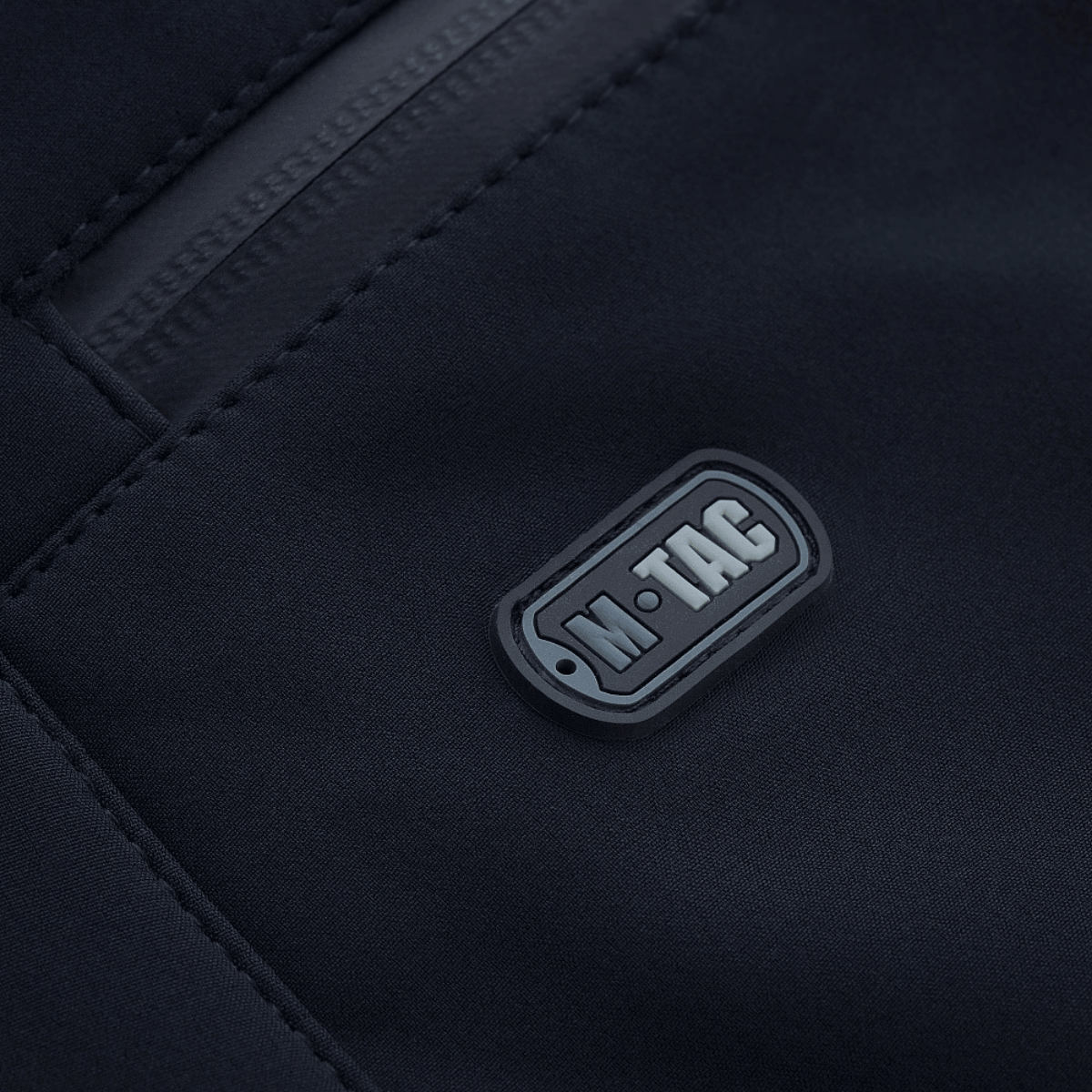 Lähikuva M-Tac Soft Shell Vinter -housuista, logo- ja vetoketjudetalji, sopivat kylmään säähän.