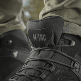 M-Tac Taktiske Sæsonstøvler mustasta nahasta ulkokäyttöön, lähikuva nauhoista ja logosta.