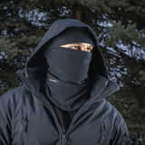 Mies käyttää M-Tac Anatominen Tube Scarf Polartec-nyörillä kasvomaskina metsäympäristössä. Polartec-fleece tarjoaa lämpöä ja suojaa.