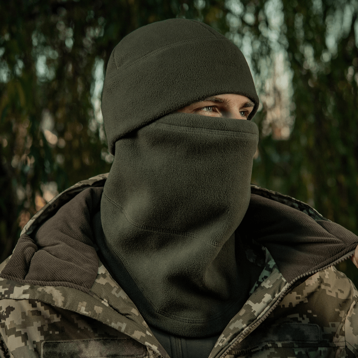 Mies pukeutuneena M-Tac Anatomisk Snood Justerbar Elite Fleece (320 g/m²) metsässä, erinomainen kylmään säähän.