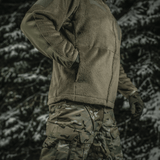 M-Tac Battle Fleece Polartec -takki käytössä armeijassa metsäympäristössä, korostaa kestävyyttä ja mukavuutta.