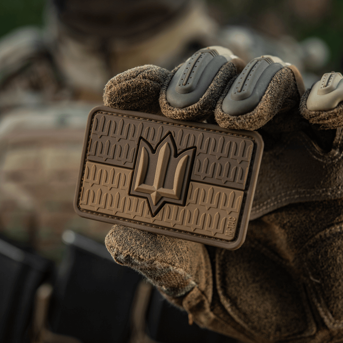Henkilö pitelee M-Tac-patchia Ukraine Flag ZSU Trident PVC, joka ilmaisee Ukrainan armeijan ylpeyden ja kansallista perintöä 3D-muotoilussa (3d en).