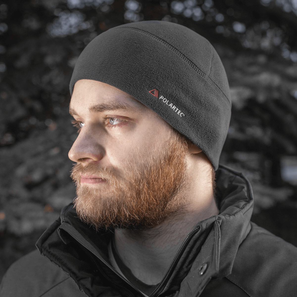 Mies pukeutunut M-Tac Fleece Watch Cap Light Polartec en mustan takin alla talvisäässä