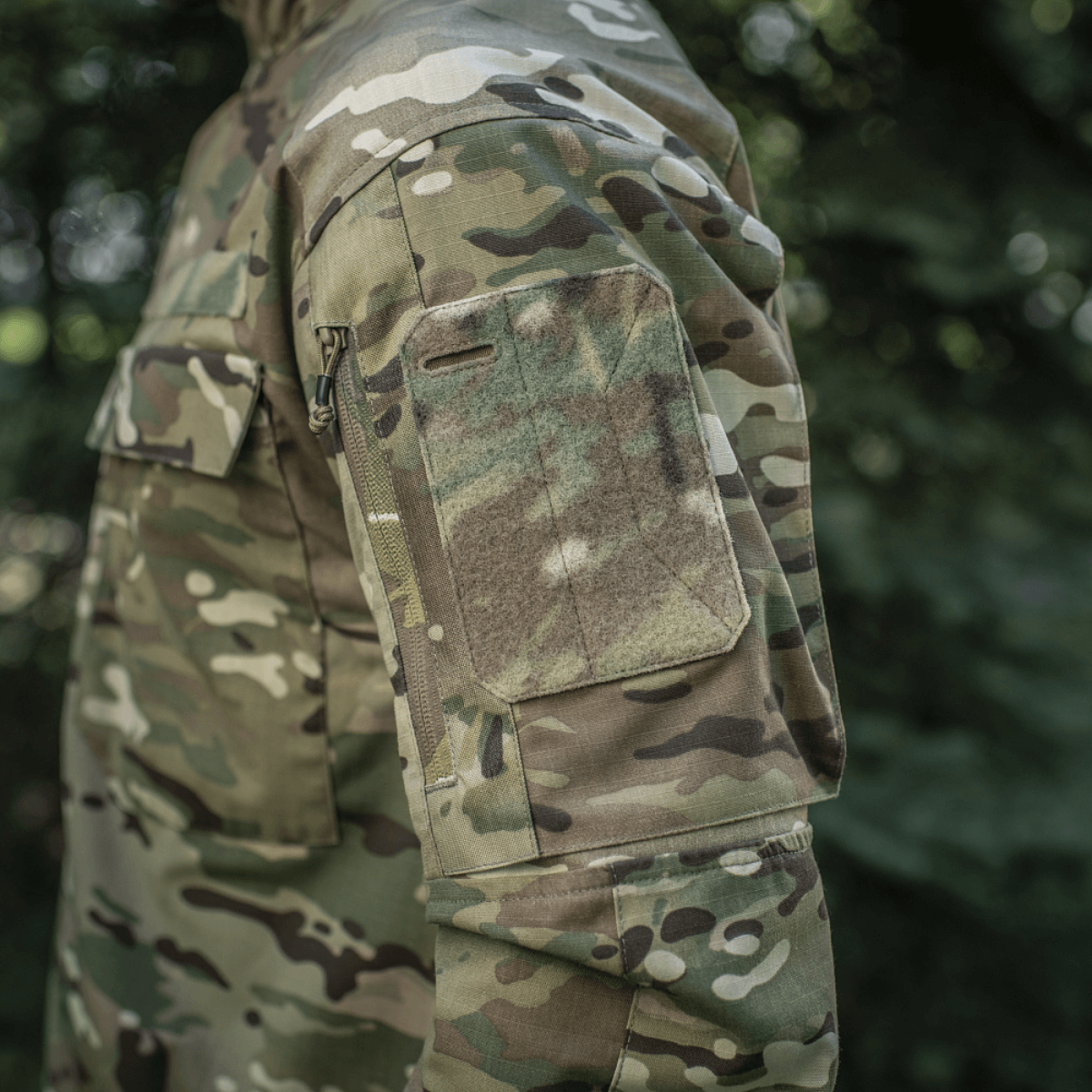 M-Tac-takki Sturm Gen.II NYCO Extreme Multicam, sivulta kuvattuna näkyvine taskuineen, sopii taktisiin ja ulkoilutoimiin.