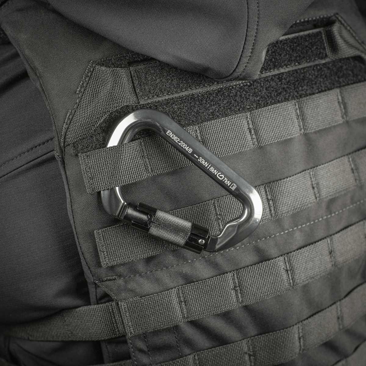 M-Tac Key-Lock karabiini kiinnitettynä taktiseen liiviin, alumiinia, automaattinen key-lock, CE EN362, 30 kN kuormitus.