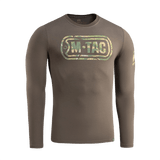 M-Tac T-Shirt Logo Long Sleeve maastokuviossa, ikoninen logo ja slogan, sopii arkeen ja taktisiin aktiviteetteihin, etupuoli näkyvissä.