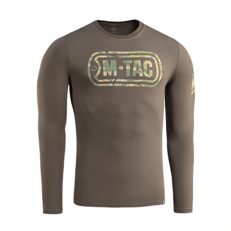 M-Tac T-Shirt Logo Long Sleeve maastokuviossa, ikoninen logo ja slogan, sopii arkeen ja taktisiin aktiviteetteihin, etupuoli näkyvissä.