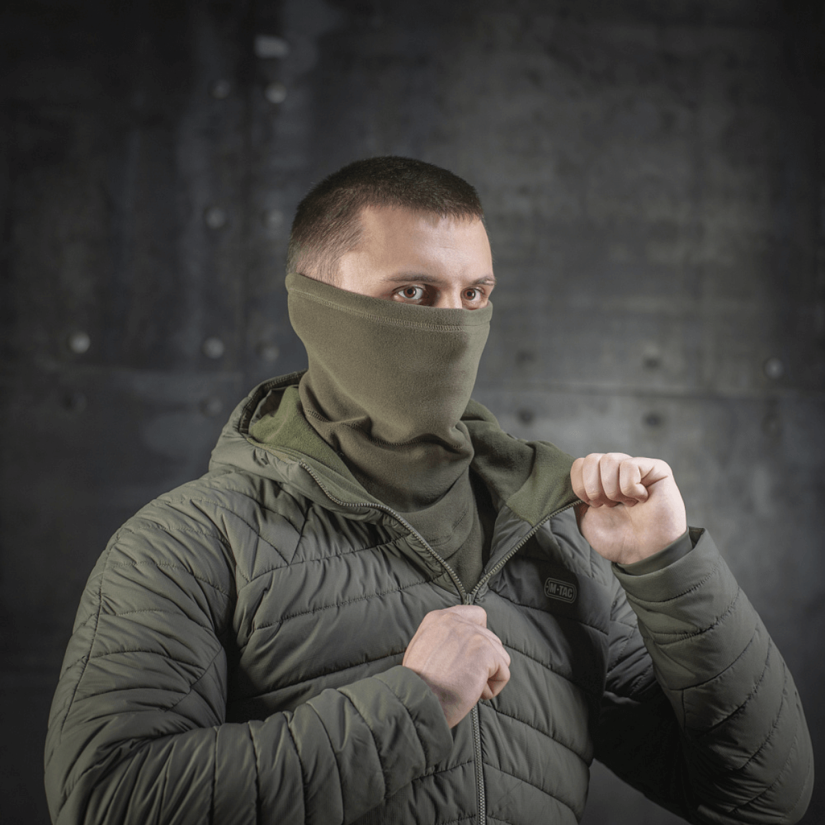 Miehellä on M-Tac Polartec Anatomic Tube Scarf kasvomaskina vihreässä ympäristössä.