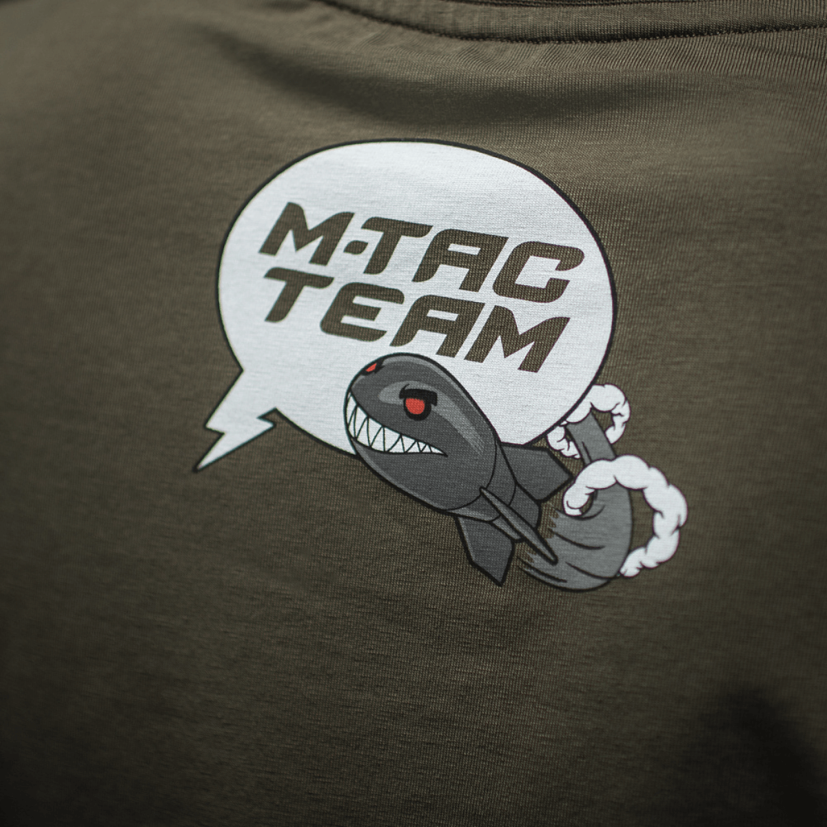 M-Tac T-Shirt Comics Drone Girl -paidassa sarjakuvapainatus, jossa pirullinen hymyilevä drooni ja teksti 'M-TAC TEAM'. Kunnioittaa ukrainalaisia droonioperaattoreita.