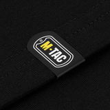 M-Tac T-Shirt Logo -yksityiskohta camokuvioinnilla ja ikonisella brändilogolla puuvillasekoitteessa. "Born by Revolution" -slogan hihassa.