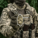 Sotilas maastopuvussa pitää M-Tac Sticker Valkyrie -tarran, jossa on sotajumalatar tyylitellyllä kypärällä ja m4-aseella.