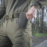 Henkilö pukeutuneena M-Tac Aggressor Summer Flex -housuihin, puhelin taskussa ulkoilupolulla.